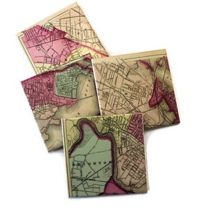 May include: A collection of square coasters featuring vintage map designs. The coasters display sections of old maps with pink, green, and beige tones. The maps show streets, rivers, and city names, creating a nostalgic and decorative item.