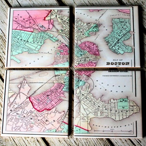May include: Set of four vintage-style ceramic coasters featuring a map of Boston and surrounding cities. The map is in shades of pink, green, and brown, with the city of Boston highlighted in pink. The coasters are perfect for adding a touch of vintage charm to your home decor.