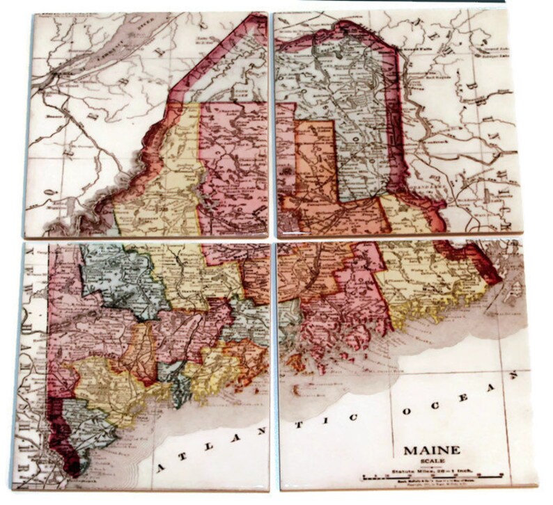 May include: Four vintage-style ceramic coasters featuring a detailed map of Maine, divided into four sections. The map is in shades of brown, red, yellow, and green, with the text "MAINE SCALE" and "Statute Miles 20 = 1 Inch" visible at the bottom.