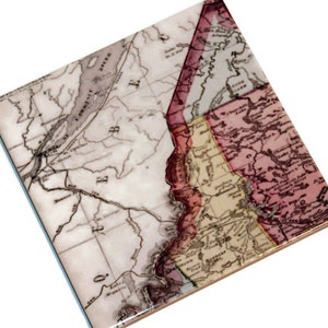May include: A vintage map of the United States, printed on a ceramic tile. The map shows the states of New York, Pennsylvania, New Jersey, Delaware, Maryland, Virginia, and North Carolina. The map is in shades of brown, red, and yellow.