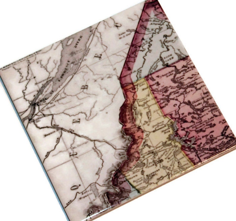 May include: A vintage map of the United States, printed on a ceramic tile. The map shows the states of New York, Pennsylvania, New Jersey, Delaware, Maryland, Virginia, and North Carolina. The map is in shades of brown, red, and yellow.