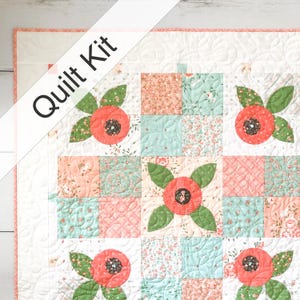 May include: A floral quilt kit featuring a patchwork design with coral, mint, and peach squares. The quilt showcases appliqued flowers with green leaves and a central black detail. The words "Quilt Kit" are printed on the upper left corner.