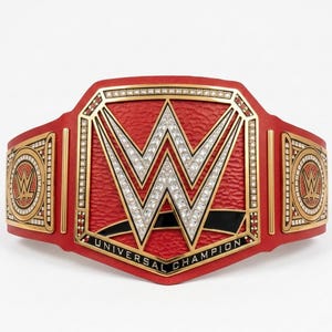 May include: A red and gold Universal Champion wrestling belt. The center plate features a large, silver "W" logo with a diamond-like pattern. The words "UNIVERSAL CHAMPION" are displayed on the bottom of the belt.