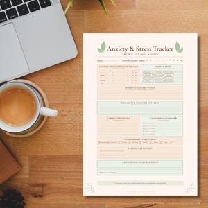 May include: A printed Anxiety & Stress Tracker sheet with a cream background, featuring sections for date, anxiety levels, energy, triggers, thoughts, coping strategies, grounding reminders, stress relief, evening reflection, and self-kindness notes.