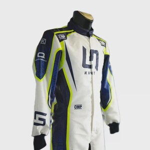 May include: White racing suit with navy blue and neon yellow accents. Features the text "KANT" and the number "5". Includes the "OMP" and "QUADRANT" logos. The suit has a high collar and black cuffs.