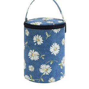 Op de afbeelding: Een cilindrische geïsoleerde lunchtas met een blauwe denim-achtige achtergrond. De tas is versierd met een patroon van witte madeliefjes en groene bladeren. Het heeft een zwarte ritssluiting en een bijpassende handgreep.