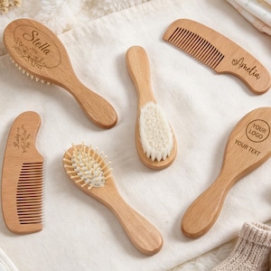 Könnte beinhalten: Eine Sammlung von hellen Holzbürsten und Kämmen für Säuglinge. Die Artikel sind mit eingravierten Namen wie Stella und Amelia, floralen Mustern und einem Platzhalter für ein Logo versehen. Das Set enthält verschiedene Borstenarten.