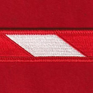 May include: A rectangular red patch with a white, angled stripe. The patch is embroidered with a red border and a white diagonal design. The background is a solid red fabric, providing a contrasting backdrop for the patch.