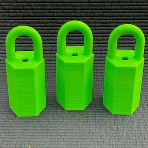 May include: Three bright green padlocks with a hexagonal body and a curved handle. The padlocks are arranged in a row, each with a small hole at the top. The background is a textured, dark gray surface.