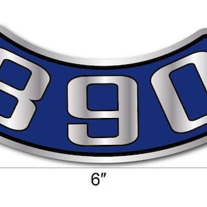 May include: A curved, blue and silver emblem with the number "390" in a stylized font. The emblem is approximately 15 cm wide. The design features a silver outline and a blue background.