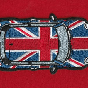 Op de afbeelding: Een geborduurde patch in de vorm van een auto, van bovenaf gezien. De auto heeft een blauw, wit en rood Union Jack-vlagpatroon op het dak en de carrosserie, met een dikke zwarte rand die de gehele vorm van het voertuig omlijnt.