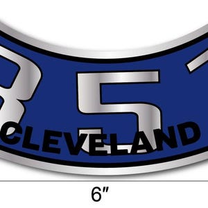 May include: A blue and silver sticker with the text "351 CLEVELAND". The sticker is 15 cm long and has a curved shape. The numbers and text are in silver, and the background is blue.