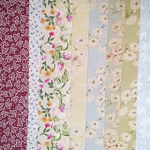 Pode incluir: Uma coleção de amostras de tecido com vários padrões florais e de folhas. A paleta de cores inclui bordô, branco, azul claro, amarelo e verde. Os tecidos apresentam diferentes desenhos florais, incluindo rosas e margaridas, e padrões de folhas.