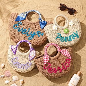 May include: Four woven straw handbags with round handles. One brown bag features a blue scarf and the name Evelyn in blue. One beige bag has white and green flower accents and the name Penny in blue. One beige bag has a purple floral scarf and the name Emma in purple. One brown bag has a pink gingham scarf and the name Jessica in pink.