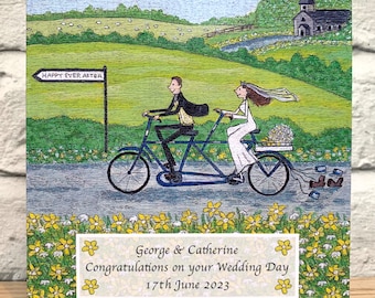 May include: A wedding card featuring a cartoon illustration of a couple riding a tandem bicycle with a sign that says "Happy Ever After". The card is decorated with yellow flowers and a church in the background. The text on the card reads "George & Catherine Congratulations on your Wedding Day 17th June 2023".