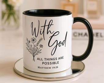 May include: A white ceramic mug with a black interior and handle. The front features a black line-art floral bouquet and the text "With God ALL THINGS ARE POSSIBLE MATTHEW 19:26" in a combination of script and sans-serif black typography.