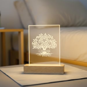 May include: A rectangular illuminated family tree night light. The clear acrylic panel features a tree design with heart-shaped leaves, each bearing a name. The base is a light-coloured wooden block. The text "Grandpa's Family" is at the base of the tree.