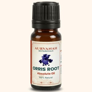 Puede incluir: Una botella de vidrio marrón con tapa negra, etiquetada como "AURVANAH BOTANICALS". La etiqueta presenta un diseño floral azul y el texto "ORRIS ROOT Absolute Oil 100% Natural."
