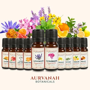 Può includere: Una collezione di flaconi di oli essenziali con tappi neri, etichettati con vari nomi botanici. I flaconi sono disposti davanti a fiori e frutti colorati, tra cui arance, limoni e lavanda. Il marchio "AURVANAH BOTANICALS" è visibile.