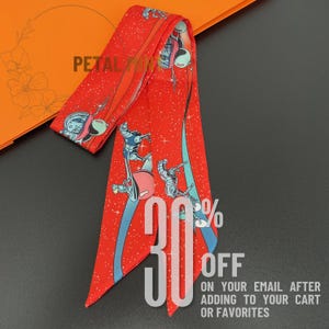 May include: A long, narrow red scarf featuring a repeating graphic print of astronauts in space suits and robotic figures against a starry background. The scarf has pointed ends and displays the text PETAL YUN at the top left corner.