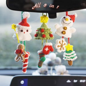 May include: A collection of eight crocheted Christmas ornaments, including a snowman, Christmas tree, and Santa Claus. The ornaments are white, red, green, and yellow, and are hanging from a car's rearview mirror. The text "All 8 in 1" is above the ornaments.