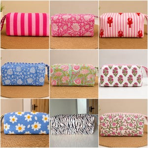 May include: A collection of nine rectangular quilted fabric pouches featuring various patterns including pink stripes, floral prints, lobster motifs, daisy prints, and zebra stripes, each with a zipper closure and a side carry handle.