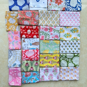 Puede incluir: Una colección de cuadrados de tela plegados con varios patrones florales y de hojas en tonos de azul, rosa, amarillo, rojo y verde. Los textiles están dispuestos en una cuadrícula, mostrando los diversos diseños.