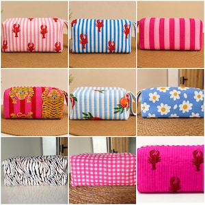 May include: A collection of nine rectangular fabric pouches featuring various patterns including red lobsters on pink or blue stripes, pink stripes, tigers, fruit, white daisies on blue, black and white zebra print, pink gingham, and red lobsters on pink.