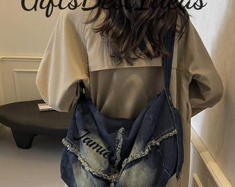 May include: A denim shoulder bag with a distressed, faded blue wash. The bag features a frayed edge design and the name "Jamie" embroidered on the front. The text "Gifts Best Ideas" is at the top.