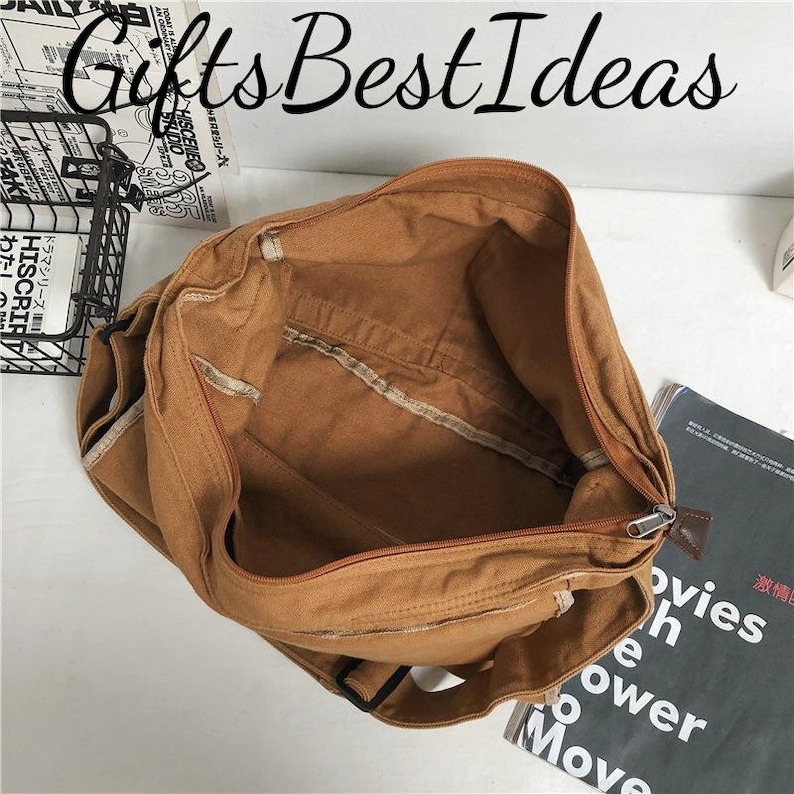 May include: A brown canvas bag with a zip closure, open to show the inside. The bag is rectangular and has a strap. The text "Gifts Best Ideas" is at the top. A magazine is visible in the background.