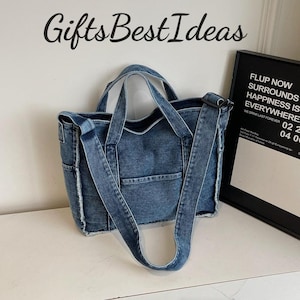 May include: A blue denim tote bag with two handles and a shoulder strap. The bag has a front pocket and side pockets. The text "Gifts Best Ideas" is above the bag. A black framed poster is to the right of the bag.