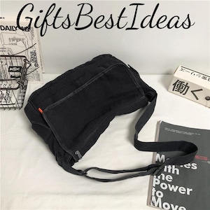 May include: A black messenger bag with a long strap, featuring a zippered main compartment and an orange accent. The bag is made of a durable fabric and has the text "Gifts Best Ideas" in a script font.