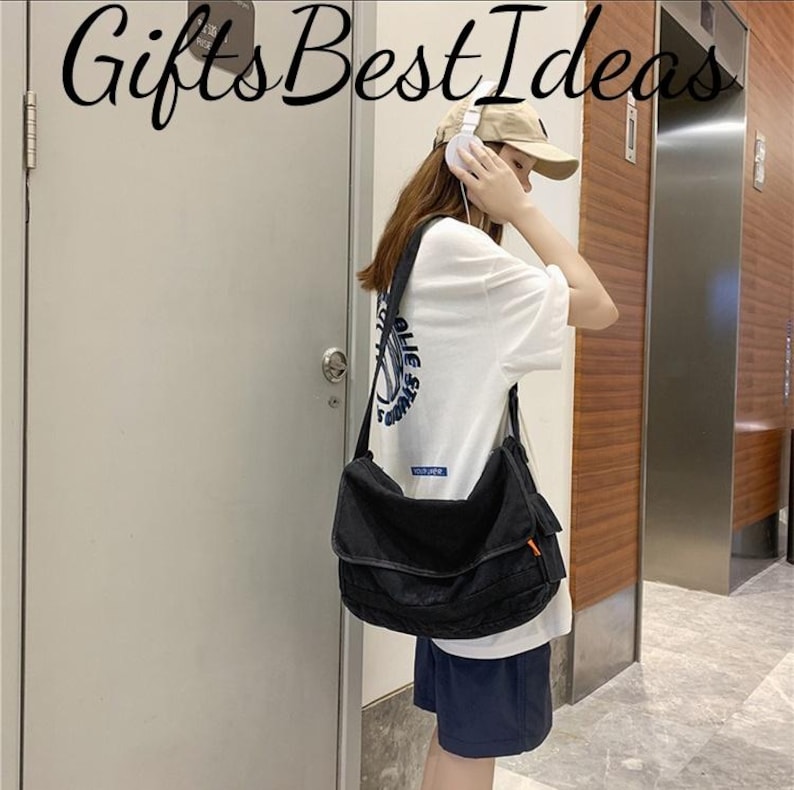 May include: A black messenger bag with a flap closure and an adjustable shoulder strap. The bag is worn over the shoulder. The image also shows a white t-shirt with blue text and a beige baseball cap. The text "Gifts Best Ideas" is at the top of the image.