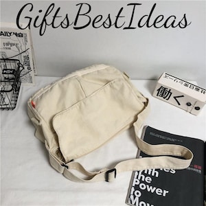 May include: A cream-coloured messenger bag with a large front pocket and an adjustable strap. The bag is rectangular with a flap closure. The text "Gifts Best Ideas" is written in cursive at the top of the image.