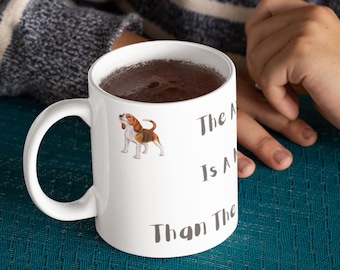 May include: White ceramic mug featuring a beagle illustration and the text "The More I Know, The Less I Know". The mug has a curved handle and is filled with a dark liquid. The mug is on a teal surface.