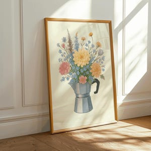 May include: A framed art print showing a watercolour illustration of a floral bouquet in a silver coffee pot. The flowers are in shades of pink, yellow, blue, and orange. The frame is light brown, and the background is cream-coloured.