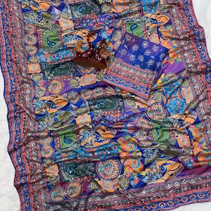 May include: A vibrant blue fabric featuring a multi-colored patchwork pattern with stylized peacock motifs, circular floral designs, and intricate borders. The textile is embellished with small reflective mirror accents throughout the surface.