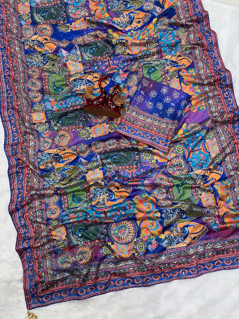 May include: A vibrant blue fabric featuring a multi-colored patchwork pattern with stylized peacock motifs, circular floral designs, and intricate borders. The textile is embellished with small reflective mirror accents throughout the surface.