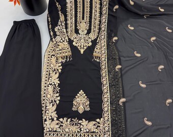 May include: A black three-piece outfit consisting of a long-sleeved tunic, trousers, and a dupatta. The tunic features intricate gold embroidery, sequins, and beadwork along the neckline, sleeves, and hem. The trousers and dupatta have matching gold embroidery.