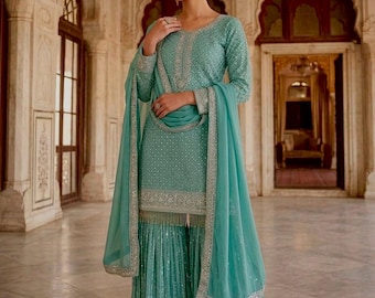 May include: A teal green three-piece ensemble featuring a long-sleeved tunic with intricate silver embroidery, matching wide-leg trousers with vertical silver stripes, and a coordinating sheer dupatta with a decorative silver border trim.