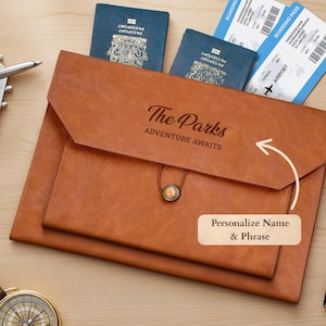 May include: A brown leather travel document holder with the text "The Parks ADVENTURE AWAITS". Passports and boarding passes are visible. A black pen and a compass are also in the image.
