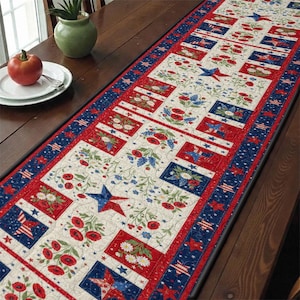 May include: A patriotic table runner with a cream-coloured centre featuring red, white, and blue floral and star patterns. The runner has a red border with floral blocks and a blue border with stars and stripes. The runner is approximately 30 cm wide.
