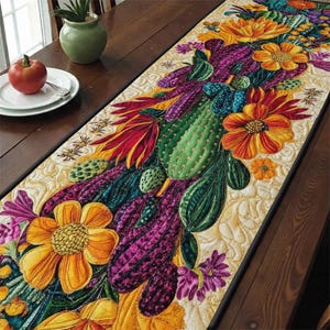 May include: A colorful, quilted table runner featuring a vibrant cactus and floral design. The runner showcases green cacti, purple and red leaves, and orange and yellow flowers. The background is a light beige with a quilted pattern.