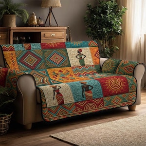 May include: A colorful sofa cover with an African-inspired design. The cover features a patchwork of geometric patterns, figures of women, and sun motifs in shades of red, orange, teal, and gold. The cover is draped over a beige sofa.