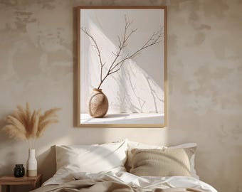 May include: A framed art print featuring a beige vase with a branch, set against a white backdrop with shadows. The artwork is in a wooden frame. The image is displayed above a bed with white bedding and a striped pillow.