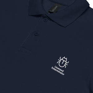 Op de afbeelding: Marineblauwe poloshirt met een wit geborduurd insectenontwerp en de tekst "Licensed Exterminator". De shirt heeft een klassieke kraag en een knoopsluiting met drie knopen. Gemaakt van een zacht, comfortabel materiaal.