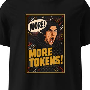 Pode incluir: Uma t-shirt preta de manga curta com uma impressão gráfica de uma pessoa de cabelo escuro a gritar. Um balão de fala acima da pessoa diz MORE! e o texto abaixo diz MORE TOKENS! em letras amarelas em negrito dentro de uma moldura.