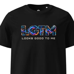 Pode incluir: Uma t-shirt preta de manga curta com um gráfico no peito que apresenta as letras LGTM num estilo líquido, iridescente e colorido. As letras incorporam teclas de teclado e um rato de computador. Abaixo do gráfico está o texto LOOKS GOOD TO ME.