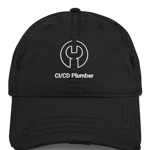 Peut inclure: Casquette de baseball noire vieillie avec un logo de clé anglaise blanc brodé et le texte "CI/CD Plumber". La casquette a une visière incurvée et un aspect vintage usé.