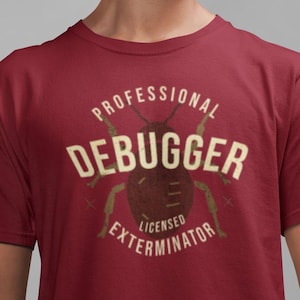 Peut inclure: T-shirt bordeaux avec un motif vieilli représentant un insecte et l'inscription "PROFESSIONAL DEBUGGER LICENSED EXTERMINATOR". Le t-shirt est à manches courtes.